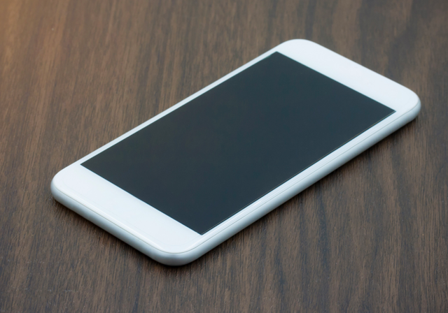 A white iPhone sitting on a table being traded in.
